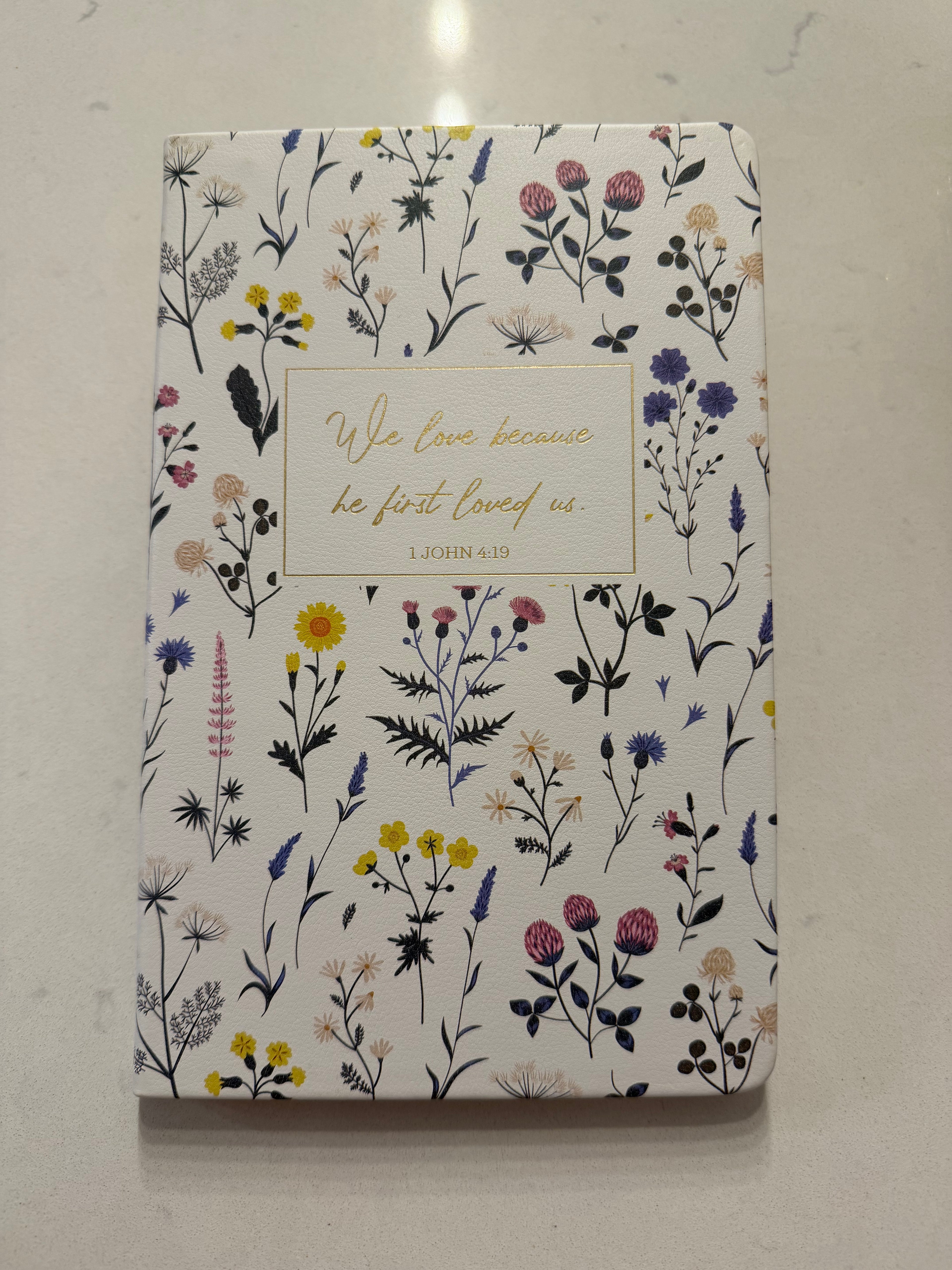 Libreta mediana Blanca Floral "1 John 4:19"
